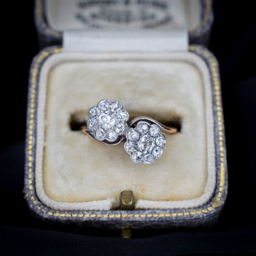 fig 1. An antique diamond ring featuring two circular daisy clusters on a crossover metal twist band.