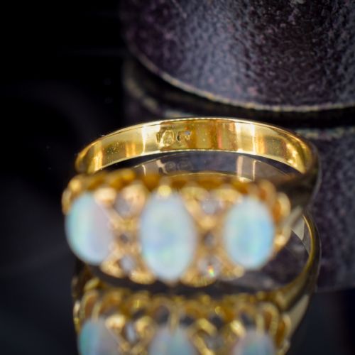 fig 1. An antique 18ct yellow gold three-stone ring featuring three oval opal cabochons flanked by small diamond accents within a carved mount.