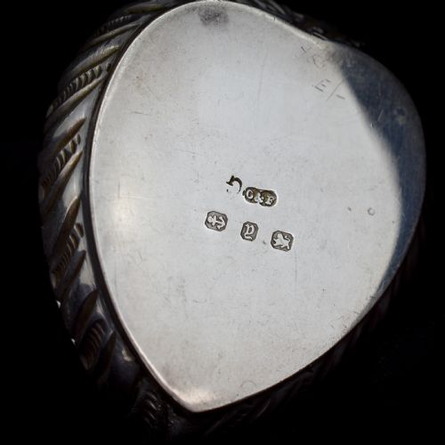 fig 2. An open heart-shaped sterling silver ring box featuring an embossed gilt interior lid and a green velvet base slot for a ring.