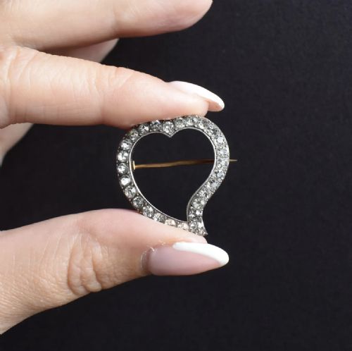 fig 1. An antique silver heart-shaped brooch featuring a classic twisted witches heart silhouette set with a row of round cut paste stones.