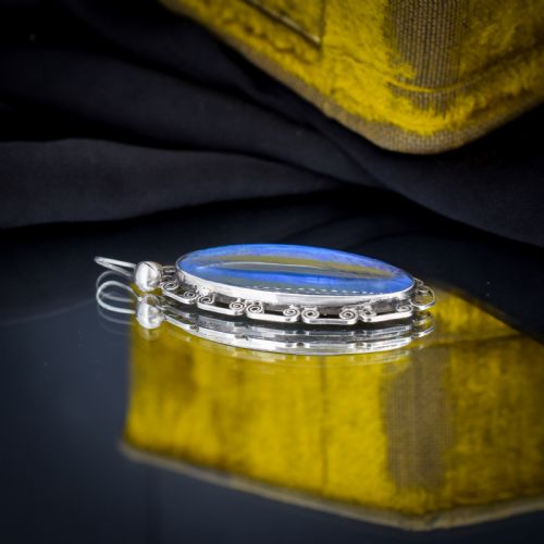fig 2. An elongated oval sterling silver Art Deco pendant enclosing a vivid blue butterfly wing with a scrolled wirework outer frame.