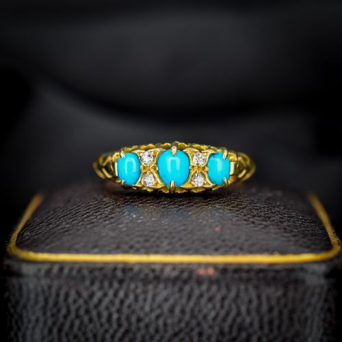 fig 1. An antique 18ct yellow gold Edwardian boat ring set with three oval turquoise cabochons and four accent diamonds, featuring carved scrollwork along the gallery.