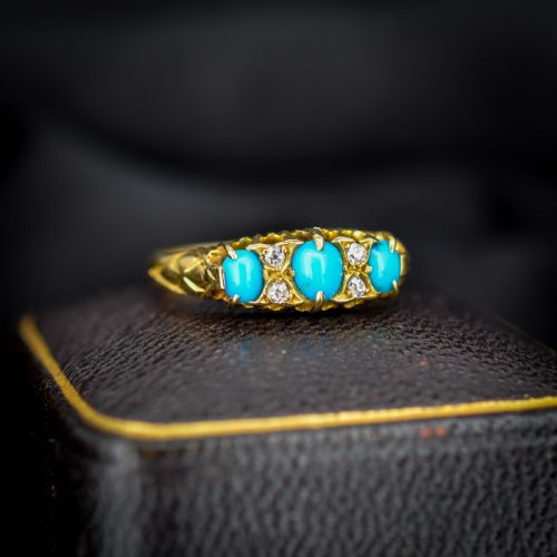 fig 2. An antique 18ct yellow gold Edwardian boat ring set with three oval turquoise cabochons and four accent diamonds, featuring carved scrollwork along the gallery.
