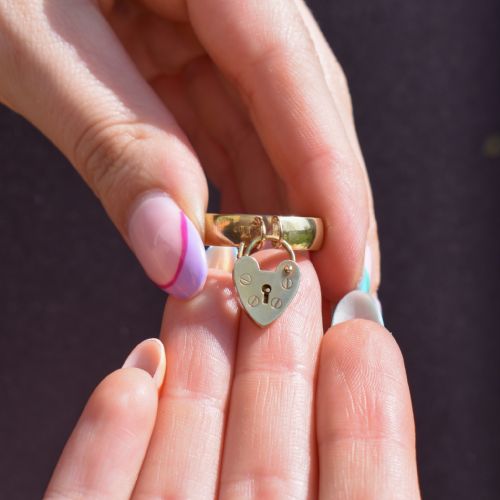 fig 1. An antique 9ct yellow gold band ring featuring a suspended heart-shaped padlock charm with keyhole and screw head details.