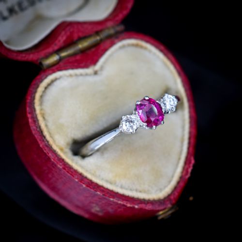 fig 1. An 18ct white gold trilogy ring featuring a central oval red ruby flanked by two round brilliant cut diamonds in claw settings.