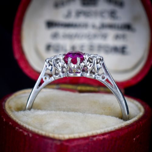 fig 2. An 18ct white gold trilogy ring featuring a central oval red ruby flanked by two round brilliant cut diamonds in claw settings.