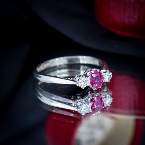 fig 3. An 18ct white gold trilogy ring featuring a central oval red ruby flanked by two round brilliant cut diamonds in claw settings.