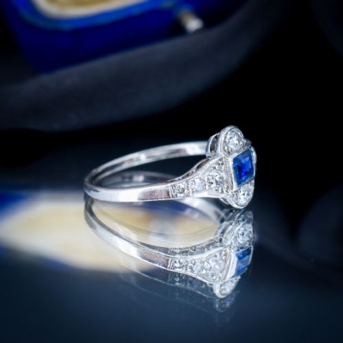 fig 2. An Art Deco platinum ring showcasing a central rectangular step-cut blue sapphire framed by small round diamonds set in a geometric, elongated mounting.