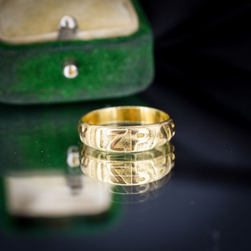 fig 1. An antique 18ct yellow gold band ring featuring the word MIZPAH in raised capital lettering against a stippled textured background.