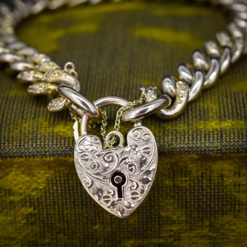 fig 1. A 9ct yellow gold curb link chain bracelet featuring alternating plain and hand-engraved links, fitted with an engraved heart-shaped padlock clasp and safety chain.