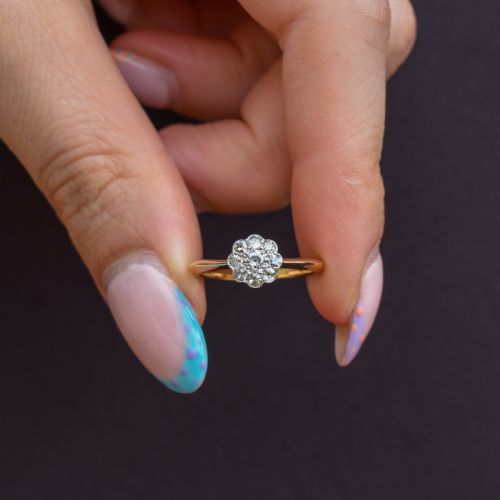 fig 1. An antique diamond daisy cluster ring set in platinum with an 18ct yellow gold band resting inside an open red heart-shaped velvet box.