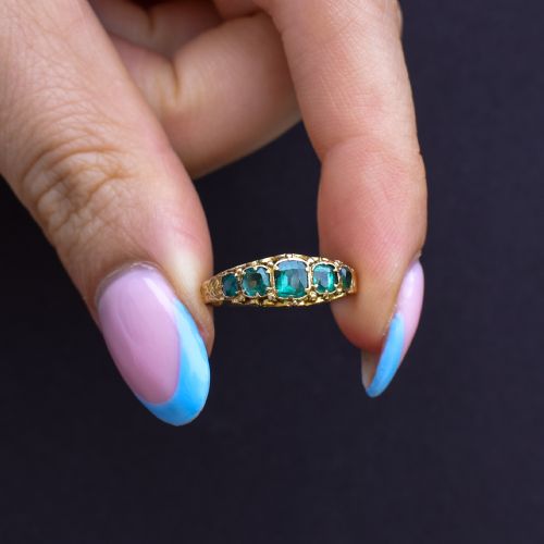 fig 1. An antique Victorian 15ct yellow gold ring featuring five graduated cushion-cut emerald green paste stones set with carved scroll shoulders.