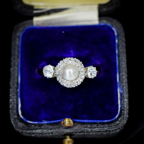 fig 1. An Edwardian 18ct yellow gold ring featuring a central round pearl framed by a halo of small diamonds and two shoulder-set diamonds.