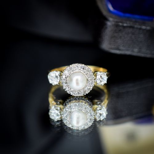 fig 3. An Edwardian 18ct yellow gold ring featuring a central round pearl framed by a halo of small diamonds and two shoulder-set diamonds.