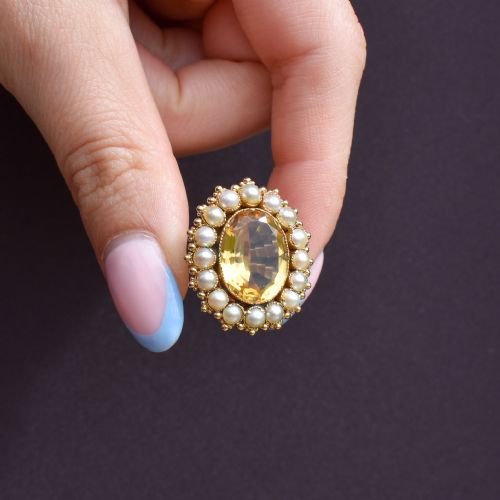 fig 2. An antique yellow gold ring featuring a central oval faceted yellow citrine stone surrounded by a halo of white seed pearls.