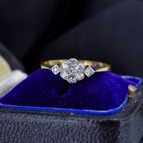 fig 1. An Edwardian cluster ring crafted in yellow gold and platinum, featuring a central round diamond surrounded by a halo of diamonds with diamond-set shoulders.