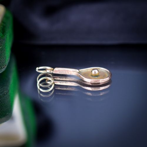fig 1. A small antique 9ct rose gold charm shaped like a tennis racket with a raised central tennis ball.