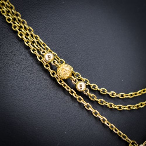 fig 1. An antique Victorian 15ct yellow gold long fancy link guard chain necklace styled in multiple tiers, featuring pattern-carved gold beads and a swivel clasp hanging at the centre.