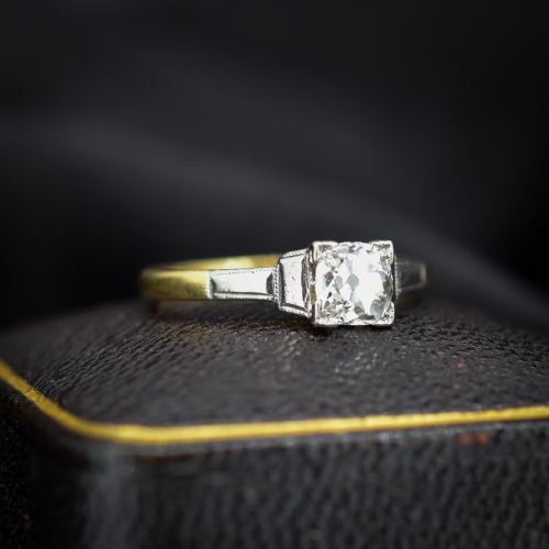 fig 1. An Art Deco engagement ring featuring a square-set central old cut diamond on an 18ct yellow gold band with white metal stepped shoulders.