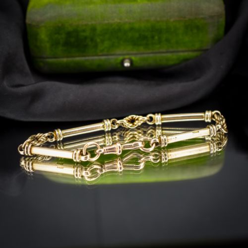 fig 1. An antique 9ct yellow gold bracelet featuring elongated tubular bar links interspersed with love knot connections and a dog clip clasp.