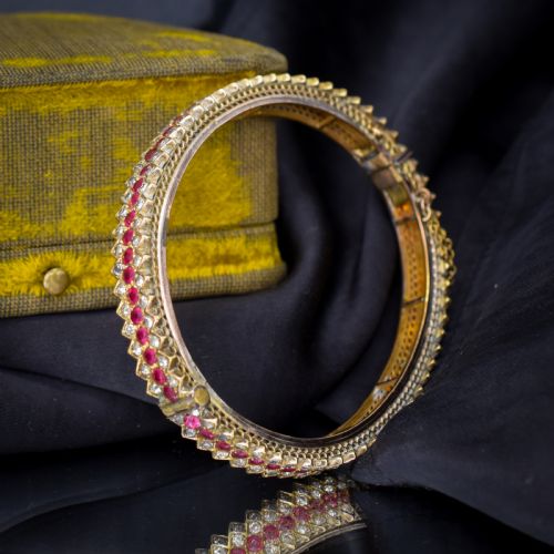 fig 1. An Art Deco hinged bangle featuring a geometric chevron pattern set with alternating rows of clear and red round-cut paste stones.