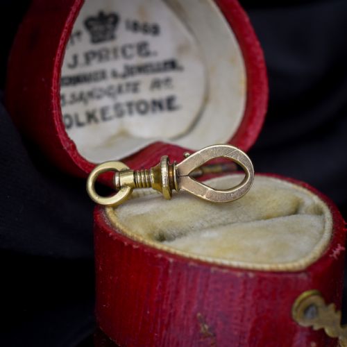 fig 1. An antique 15ct yellow gold screw dog clip fastener resting on a red heart-shaped presentation box.