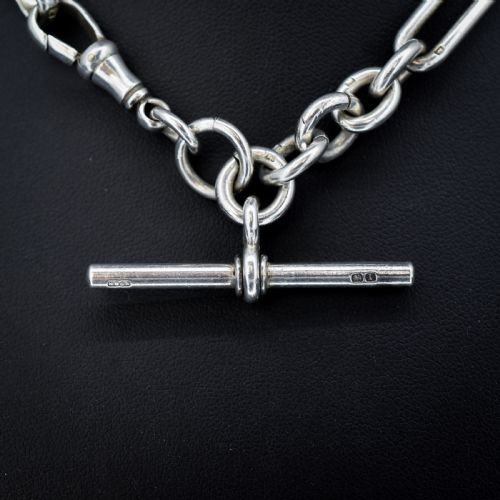 fig 2. An antique Edwardian sterling silver trombone link Albert watch chain featuring a T-bar and swivel clasp displayed on a velvet background.