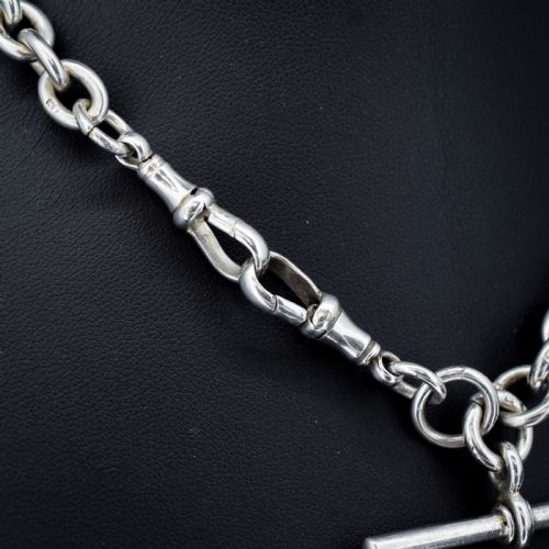 fig 3. An antique Edwardian sterling silver trombone link Albert watch chain featuring a T-bar and swivel clasp displayed on a velvet background.