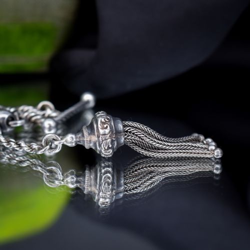 fig 3. An antique silver Albertina watch chain styled as a bracelet, featuring multi-strand rope chains, an engraved heart motif charm, a silver tassel, a T-bar, and a swivel clasp.
