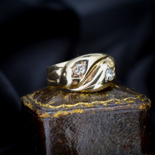fig 1. A yellow gold band featuring two entwined snake heads, each set with a star-engraved diamond.