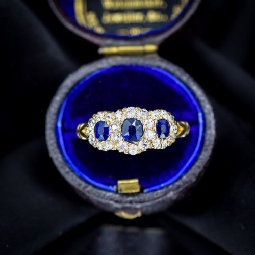 fig 2. An 18ct yellow gold Victorian ring featuring three oval blue sapphires, each encircled by a cluster of small diamonds.