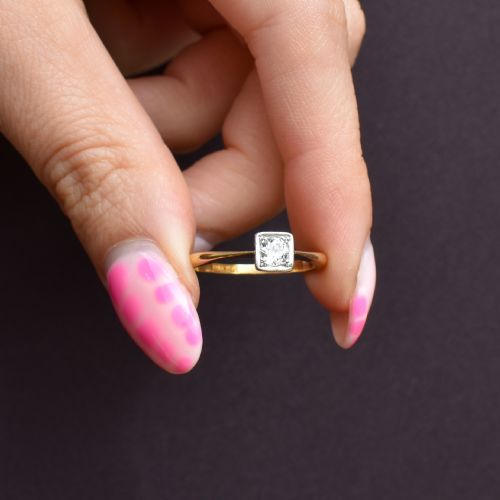 fig 1. An antique 18ct yellow gold solitaire ring holding a central round old cut diamond within a square white metal setting.