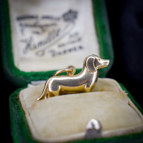 fig 1. A solid 9ct yellow gold dachshund dog charm featuring detailed eye engravings and visible hallmarks along its body.