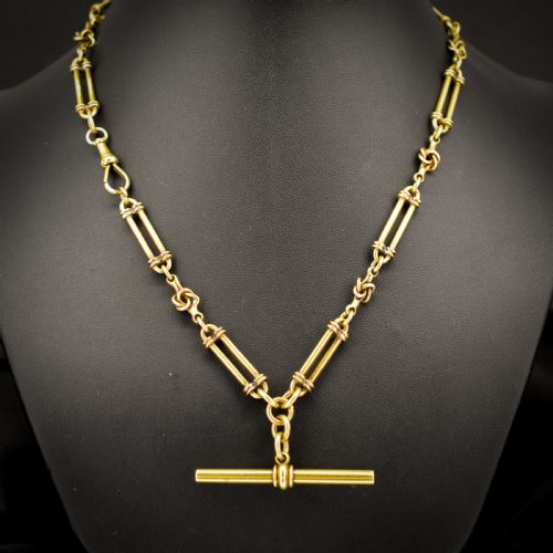 fig 1. An antique 18ct yellow gold Albert chain necklace displaying alternating trombone links and twisted love knots with a T-bar attachment.