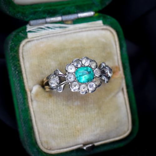 fig 1. An antique Georgian cluster ring featuring a central cushion-cut green paste stone surrounded by clear paste stones set in silver and gold.
