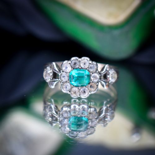 fig 2. An antique Georgian cluster ring featuring a central cushion-cut green paste stone surrounded by clear paste stones set in silver and gold.