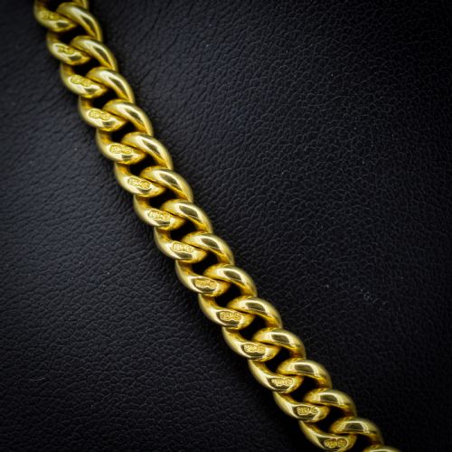 fig 2. An 18ct yellow gold curb link Albert chain necklace featuring a central ring with a T-bar drop, displayed on a black jewellery bust.