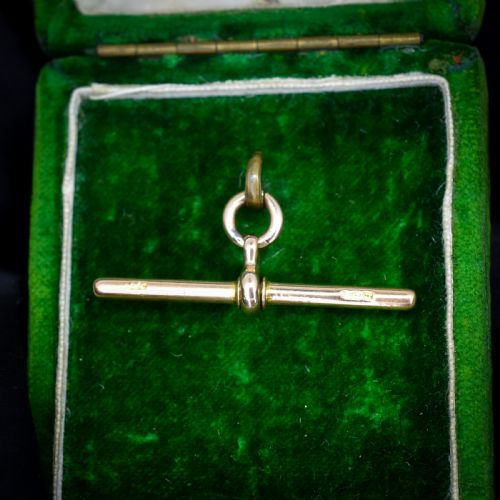 fig 1. An antique 15ct yellow gold T-bar pendant featuring a smooth crossbar, central jump rings, and stamped British hallmarks.