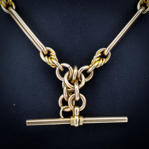 fig 2. A 9ct yellow gold Albert chain featuring alternating elongated trombone links and textured love knot links with a T-bar and swivel clasp.