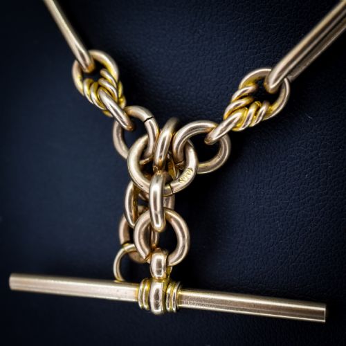 fig 3. A 9ct yellow gold Albert chain featuring alternating elongated trombone links and textured love knot links with a T-bar and swivel clasp.