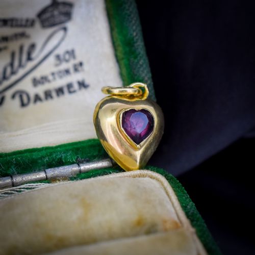 fig 1. An antique yellow gold puffy heart-shaped charm featuring a central heart-cut purple amethyst paste gem.