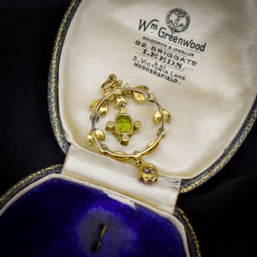 fig 2. An Edwardian 15ct gold openwork lavalier pendant set with seed pearls, featuring an oval green peridot central stone and a suspended round purple amethyst drop.