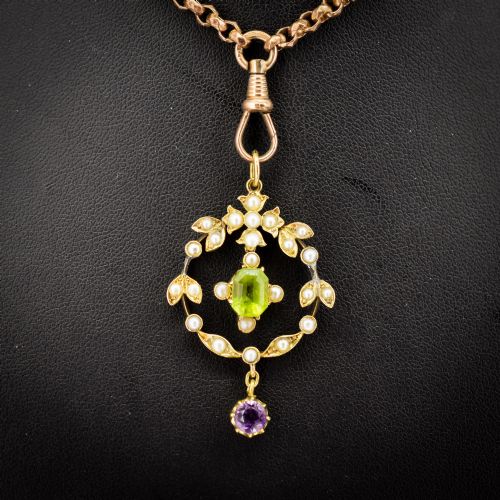 fig 3. An Edwardian 15ct gold openwork lavalier pendant set with seed pearls, featuring an oval green peridot central stone and a suspended round purple amethyst drop.