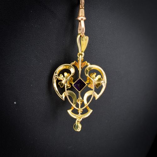 fig 3. An ornate openwork 15ct gold Edwardian pendant decorated with seed pearls, a square central amethyst, and a hanging round peridot drop.