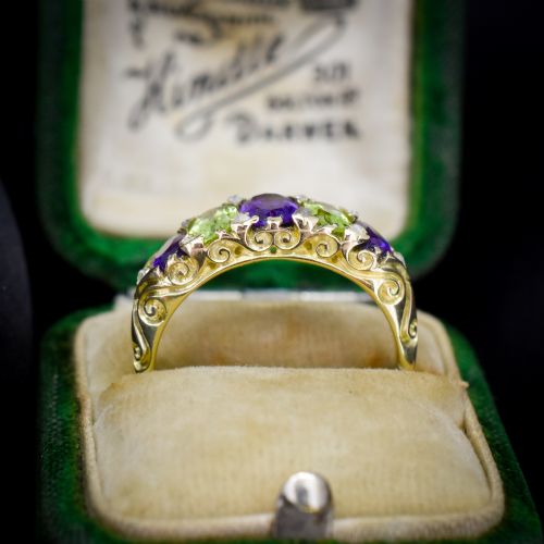fig 1. An antique 18ct yellow gold five-stone ring featuring alternating oval amethysts and peridots set with small diamond accents in a carved gallery.