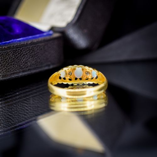 fig 2. An Edwardian 18ct yellow gold boat ring set with three cabochon natural opals and two small diamonds within a carved scrollwork gallery.