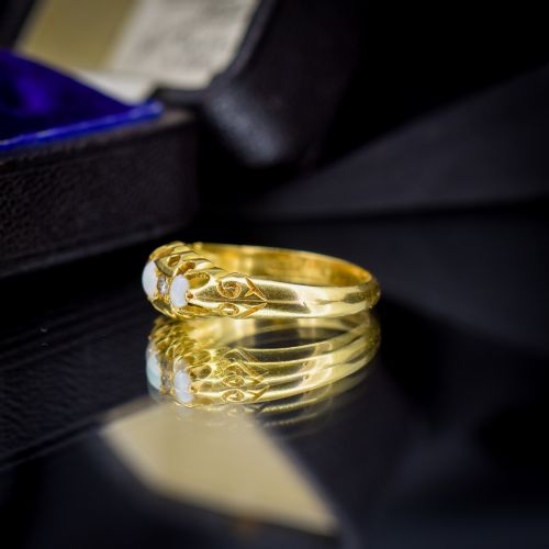 fig 3. An Edwardian 18ct yellow gold boat ring set with three cabochon natural opals and two small diamonds within a carved scrollwork gallery.