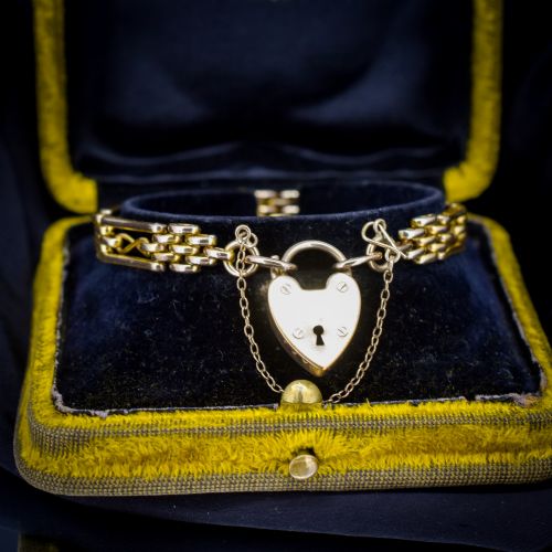 fig 1. An antique rolled gold gate link bracelet featuring multi-row interlocking bars and a central heart-shaped padlock clasp with a safety chain.