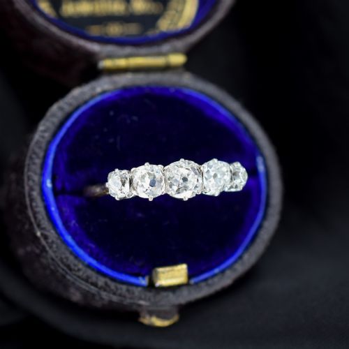 fig 1. An antique five-stone ring featuring five graduated old cut diamonds set in a row mounted on a gold band.