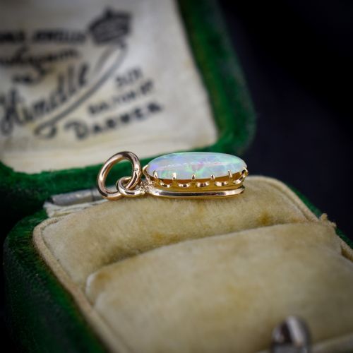 fig 1. An oval natural opal cabochon pendant held in a multi-claw yellow gold setting with an attached jump ring.